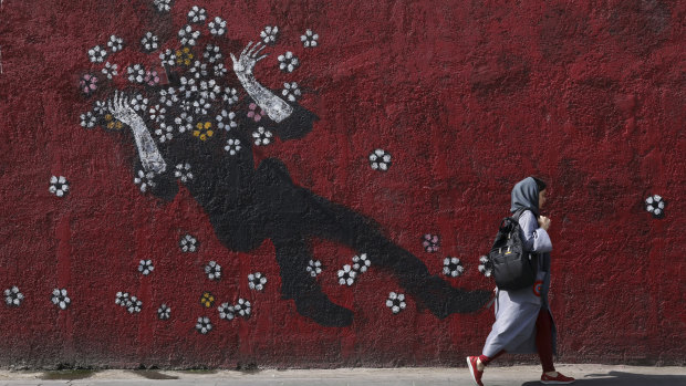 A woman walks past a mural in downtown Tehran, Iran, on Sunday.