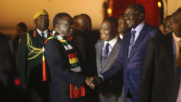 Zimbabwean President Emmerson Mnangagwa, left, is greeted as he arrives at Robert Mugabe International Airport in Harare on Monday.