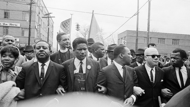 Martin Luther King jnr, fourth from left, foreground, locks arms with his aides as he leads a march of several thousand to the courthouse in Montgomery, Alabama. From left are: an unidentified woman, Reverend Ralph Abernathy, James Foreman, King, Jesse Douglas snr and John Lewis. 