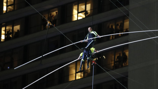 Aerialists Nik Wallenda, top, steps over his sister Lijana as they walk on a high wire above Times Square, New York.