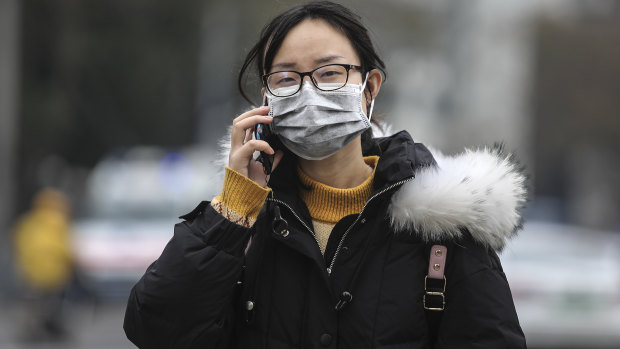 A woman wears a mask while walking past the closed Huanan Seafood Wholesale Market, which has been linked to cases of Coronavirus, in Wuhan.