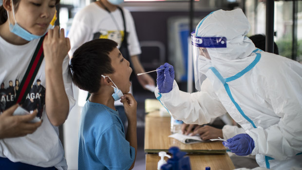 A medical worker takes samples during a mass COVID-19 test in a residential block of Wuhan.