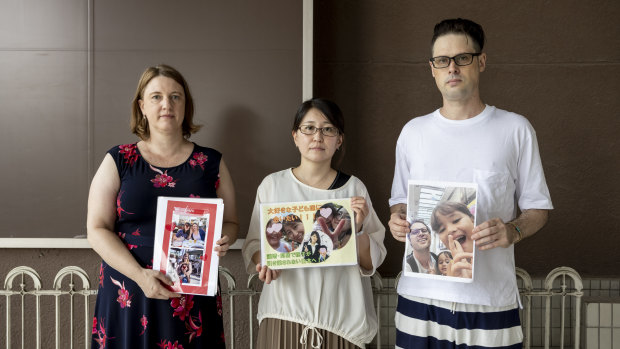 Catherine Henderson, Izumi Dobashi and Scott McIntyre hold photos up of their children. 