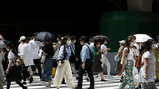 Pedestrians wearing protective face masks cross the road at Umeda district in Osaka.