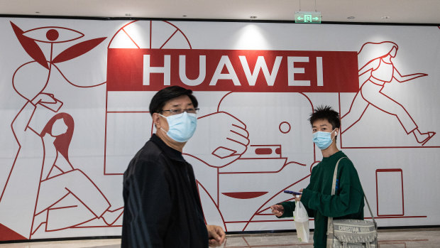 Ziyaretçiler, Wuhan'daki dünyanın en büyük tek alışveriş merkezi olan Wushang Dream Plaza alışveriş merkezindeki bir Huawei mağazasının önünden geçiyor.