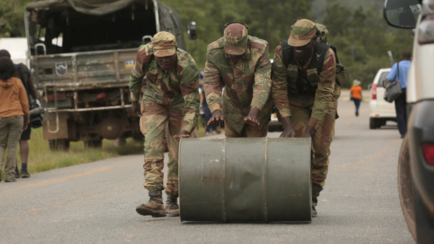 Soldiers push a drum of jet fuel used in rescue operations in Chimanimani.