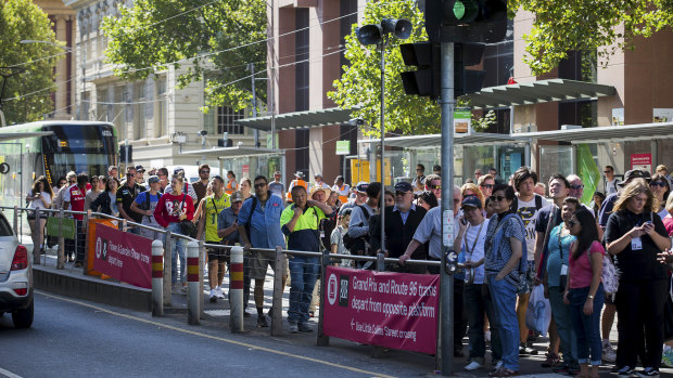 Sports fans crowd a tram stop at the corner of Collins and Spencer streets.