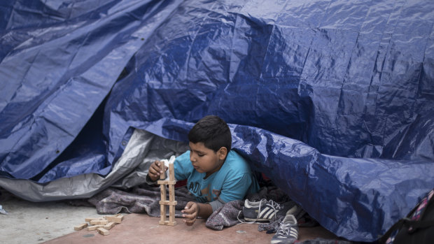 A migrant child from El Salvador plays under a tarpaulin at the El Chaparral port of Entry, in Tijuana, Mexico, on Monday.