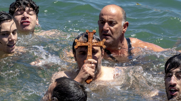 Dozens of men took part in the swim for the wooden cross tossed into Port Phillip Bay.