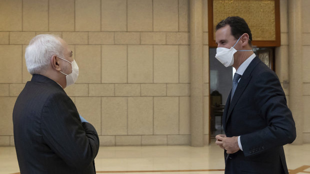 Syrian President Bashar Assad, right, wears a mask to help protect from the coronavirus, as he speaks with Iranian Foreign Minister Mohammad Javad Zarif, who also wore a mask and gloves, in Damascus, Syria.