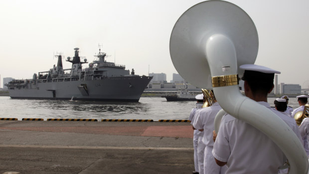 Japan Self-Defence Forces marching band members perform as British Royal Navy's HMS Albion amphibious assault ship arrives at a dock in Tokyo.