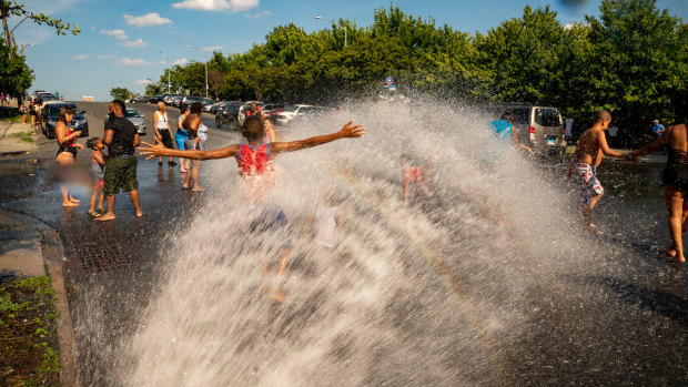 People stand in the spray of water coming from a fire hydrant in the Bronx borough of New York.