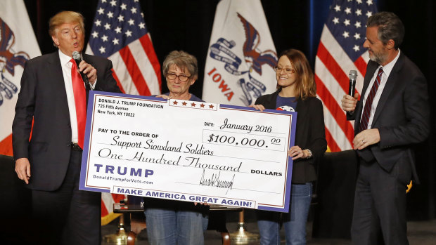 Donald Trump, left, stages a check presentation with an enlarged copy of a $100,000 contribution from the Donald J. Trump Foundation to Support Siouxland Soldiers during a campaign event in Sioux City, Iowa., during Trump's run for president. New York Attorney General Barbara Underwood filed a lawsuit accusing Trump of illegally using his charitable foundation to pay legal settlements and campaign costs.