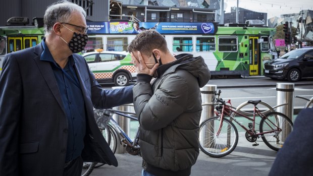 Small business owner Bill Panayotou is comforted after he got emotional talking about his business woes during lockdown outside Flinders Street Station.