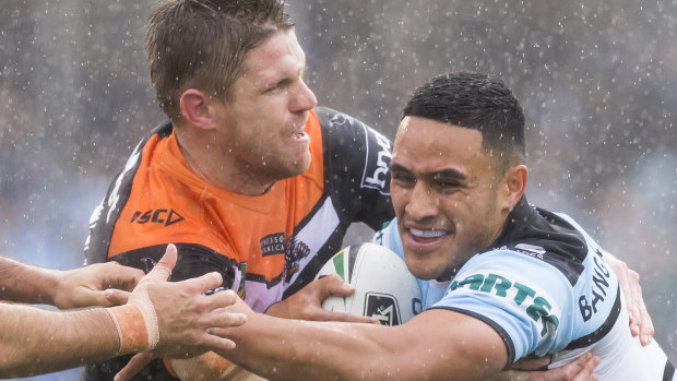 Slippery Shark: Cronulla's Valentine Holmes clashes with Wests Tigers' Chris Lawrence on Sunday afternoon.