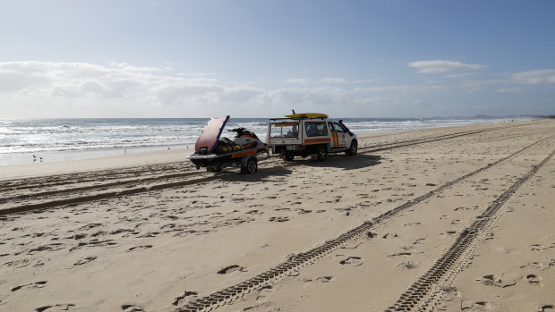 Surf Rescue crew drive past the scene where the body of an infant was found at Surfers Paradise on Monday.