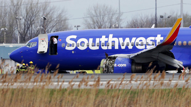 The Southwest Airlines plane sits on the runway with a damaged engine on the left side.