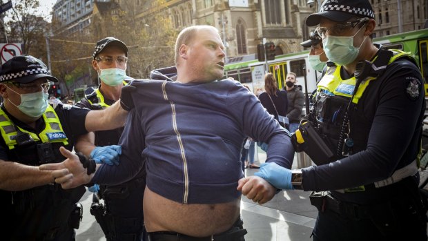 An anti-vaccination protester is arrested outside Flinders Street Station after hijacking a demonstration by small business owners. 