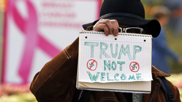 A man holds a sign outside the University of Pittsburgh's Presbyterian Hospital before the arrival of President Donald Trump's motorcade.