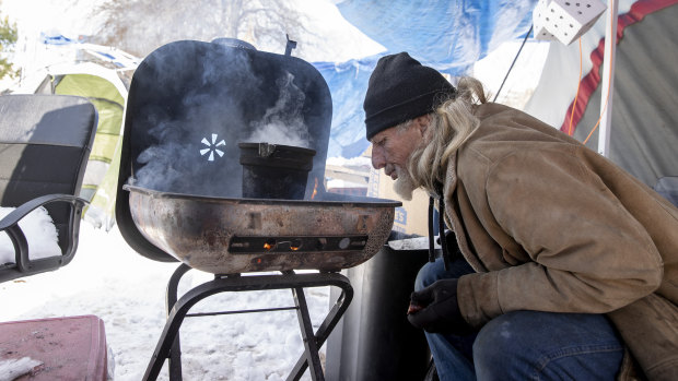 Hawk Palmour tends a fire he used for heat and cooking at a homeless camp in Austin, Texas.