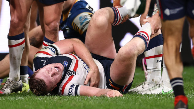 Drew Hutchison of the Roosters writhes in pain. He was sent to hospital with suspected broken ribs. 