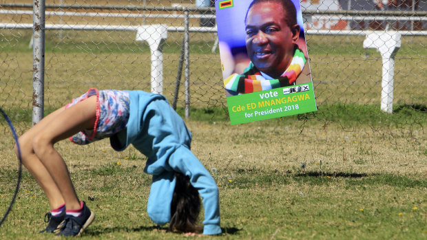 A child plays next to Zimbabwean President Emmerson Mnangagwa's election campaign poster during a rally organised for the white community in Harare on Saturday.