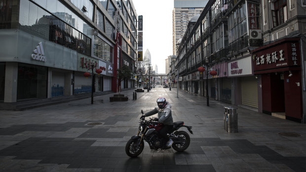 A man rides a motorcycle in an empty business street in Wuhan, Hubei province, China. 