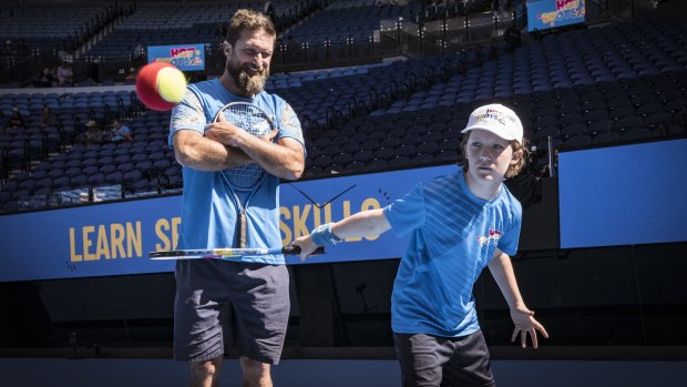 Tennis coach Paul Rowbottom teaches his daughter Edie about the finer points of the slice backhand on Rod Laver Arena.