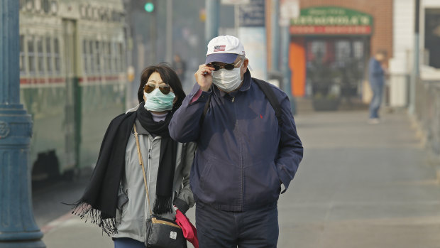 A couple wears masks while walking at Fisherman's Wharf in San Francisco.