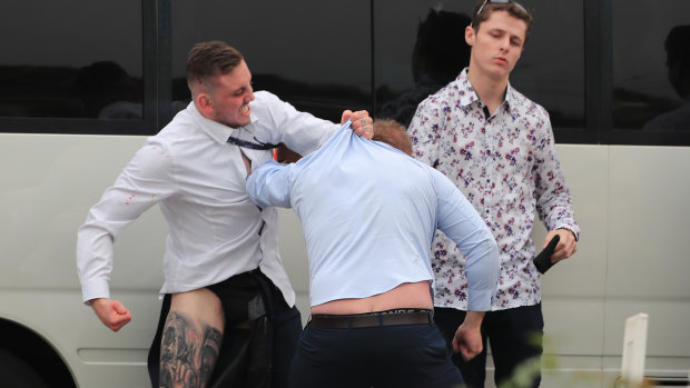 A Rosehill patron looks unimpressed as two  brawlers go toe to toe.