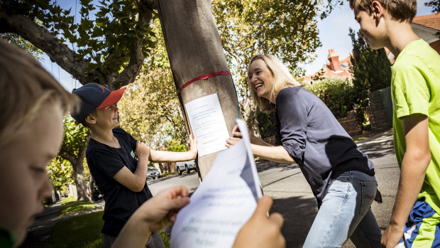 Kate Adamson and her sons; Banjo 11, Rupert 9 and Alastair 6, pin posters up around Elwood's streets offering help to the elderly during the coronavirus pandemic. 