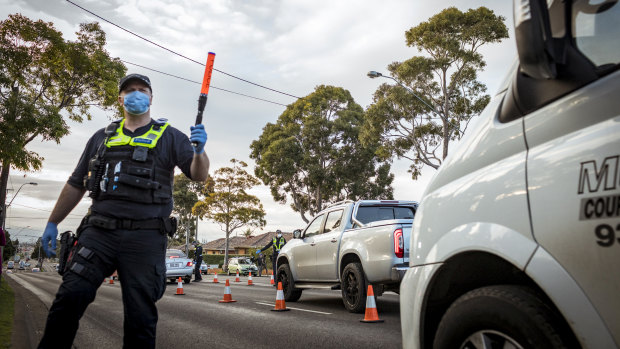 Police at a road block enforce lockdowns in one of 10 Melbourne postcodes after a spike in coronavirus cases.