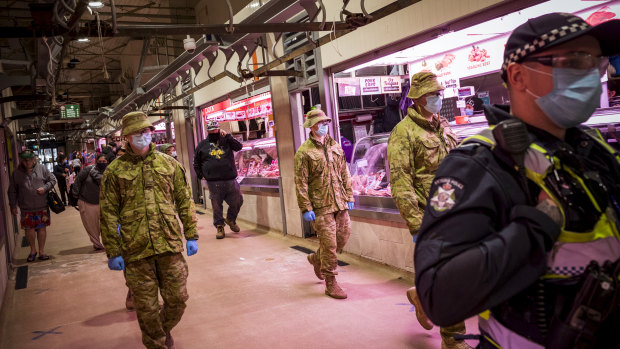 Members of Victoria Police, aided by ADF soldiers, patrol the Queen Victoria Market.