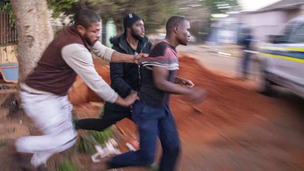 Nigerian foreign nationals remove a looter from their shops in Troyville, Johannesburg, and take him to a waiting police van on Monday.