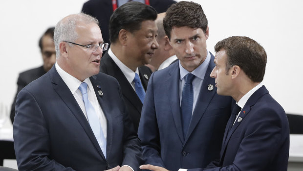 Chinese President Xi Jinping walks past as PM Scott Morrison talks with Canada's Justin Trudeau and France's Emmanuel Macron at the G20 in Osaka.