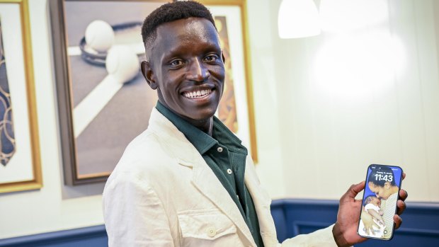 Proud father Peter Bol shows off a photo of fiancee Mahtut Yaynu and baby Reyna. 