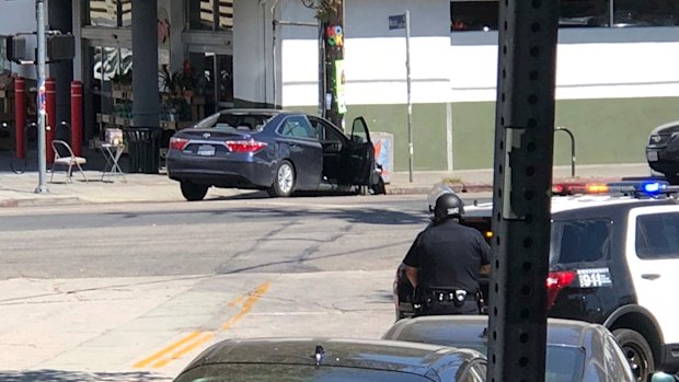 Police officers stand guard near a crashed vehicle outside a Trader Joe's store in Los Angeles on Saturday.