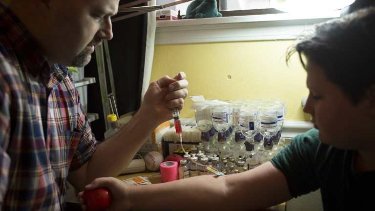 Nathan Wilkes performs an intravenous infusion of clotting factor concentrate for his son, Thomas, who has haemophilia, in Englewood, Colorado.