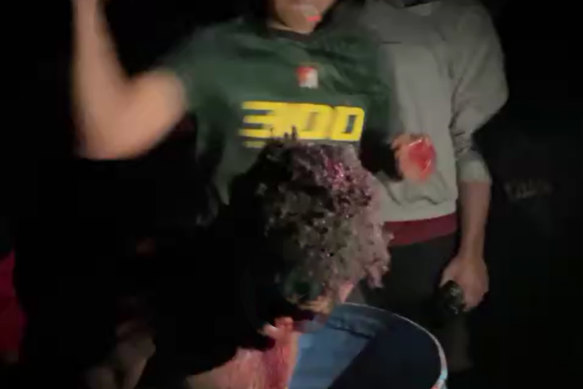 A screengrab from the footage, which shows the man standing in a barrel of bloodied water as he is beaten and cut by a mob.