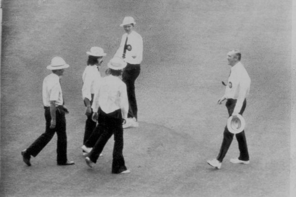 Police escort bogus umpires Gerard Noonan and Damien Bonnice from the MCG as umpires Tom Brooks and Robin Bailhache return to the field.
