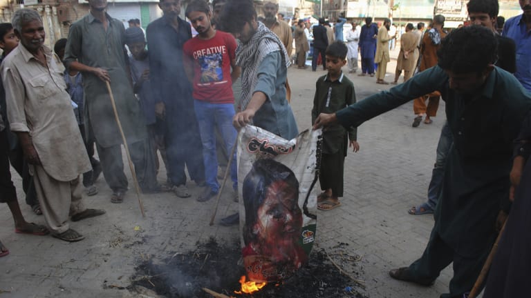 Pakistani protesters burn a poster image of a Christian woman, Asia Bibi, who has spent eight-years on death row accused of blasphemy and been acquitted by a Supreme Court, in Hyderabad, Pakistan.