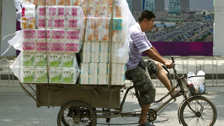 A tricycle porter transports packs of toilet paper in Beijing.