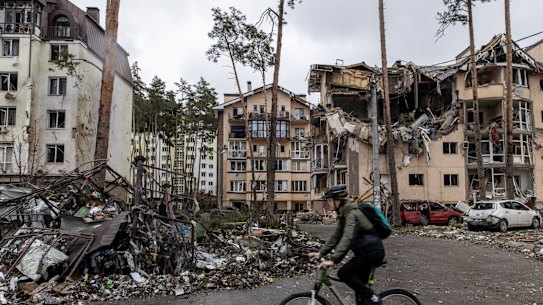 A man rides his bike past destroyed buildings in Irpin, Ukraine. 