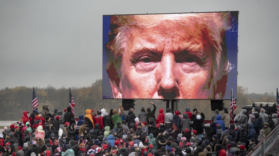 An image of Trump stands over his supporters at a Michigan rally.