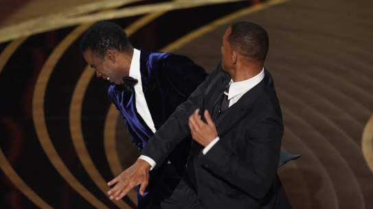 Will Smith, right, hits presenter Chris Rock on stage while presenting the award for best documentary feature at the Oscars.