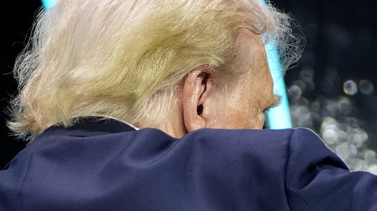 Appearing without his bandage, Donald Trump gestures towards the crowd at the Turning Point Believers’ Summit.