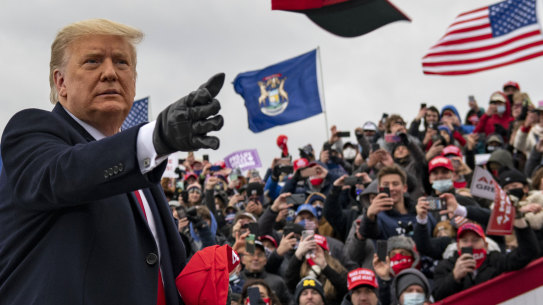 President Donald Trump tosses a cap during a campaign stop in Waterford Township, Michigan.