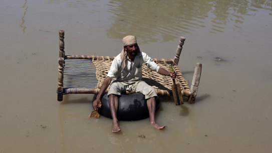 A displaced man carries belongings he salvaged from his flood-hit home as he paddles through a flooded area, on the outskirts of Peshawar, Pakistan, on Sunday.