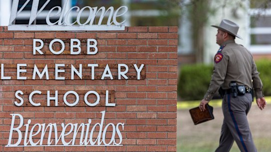 A state trooper walks past the Robb Elementary School sign in Uvalde, Texas.