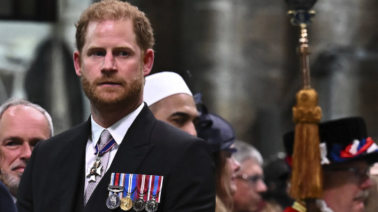 Prince Harry, Duke of Sussex, looks on as his father, King Charles III, leaves Westminster Abbey after the coronation.